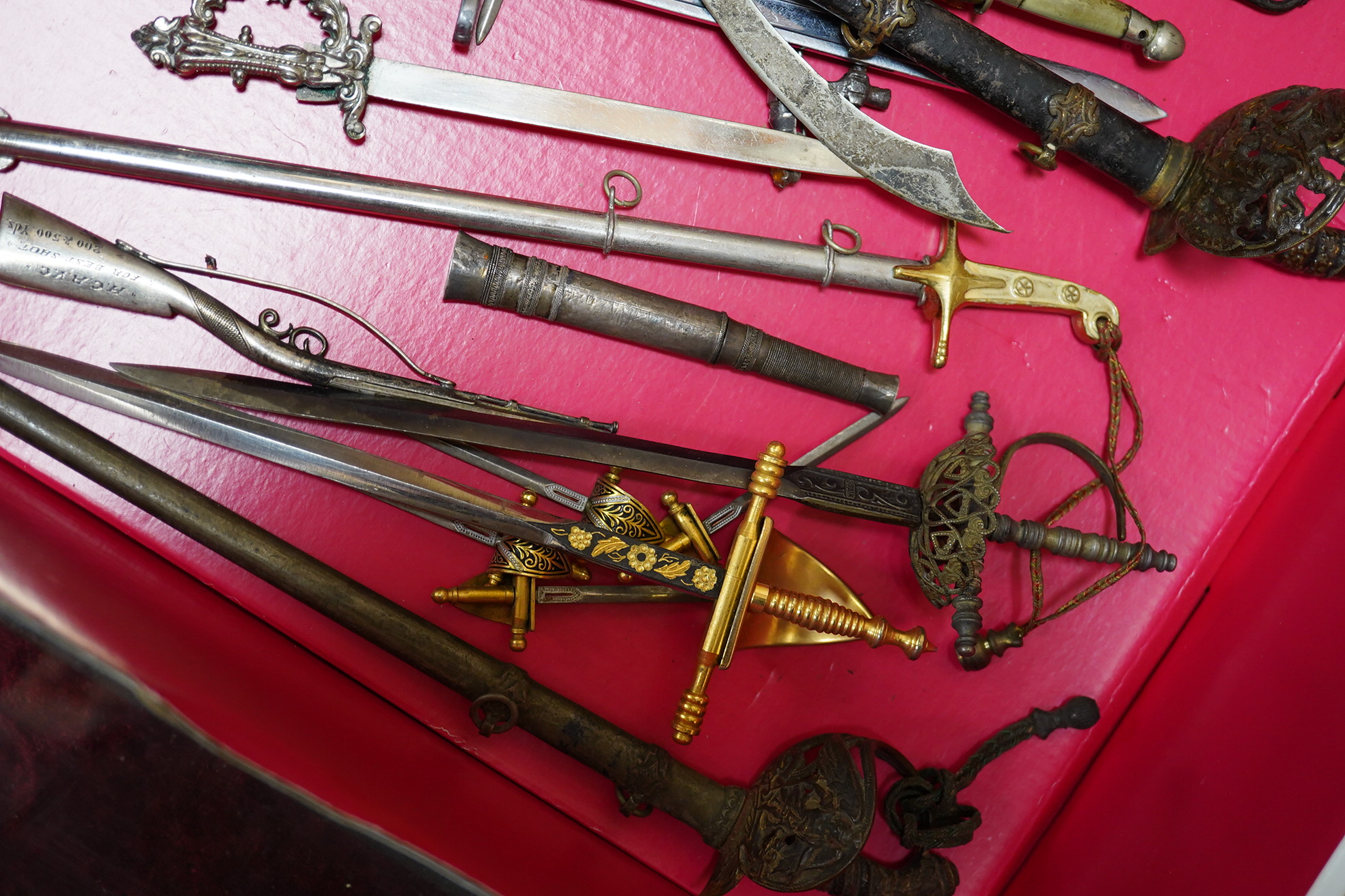 A large collection of miniature weapons, comprising approximately thirty-four edged weapons, and thirteen assorted firearms, approximately half contained within a mahogany case. Condition - fair to good